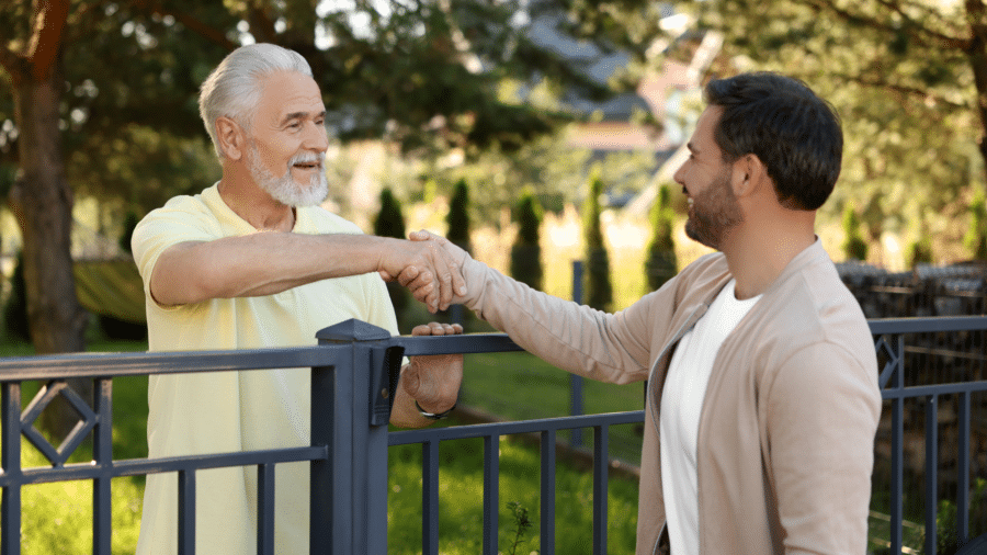 Neighbours shaking hands over a fence