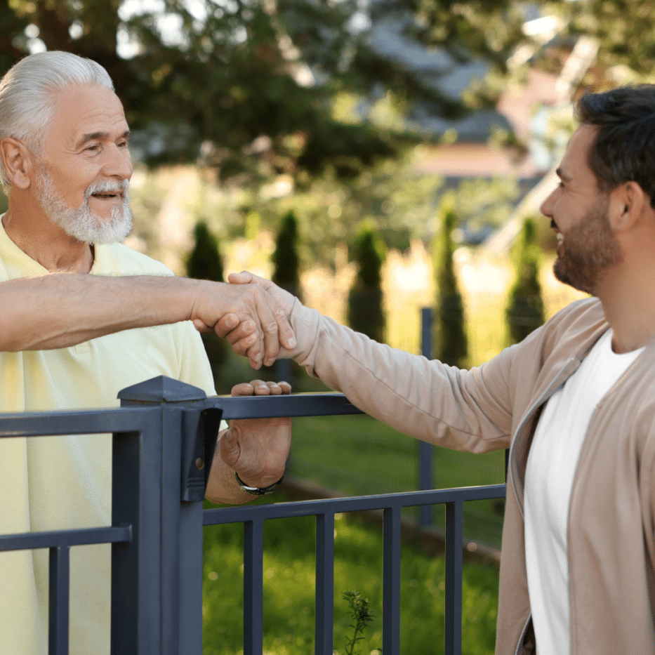 Neighbours shaking hands over a fence
