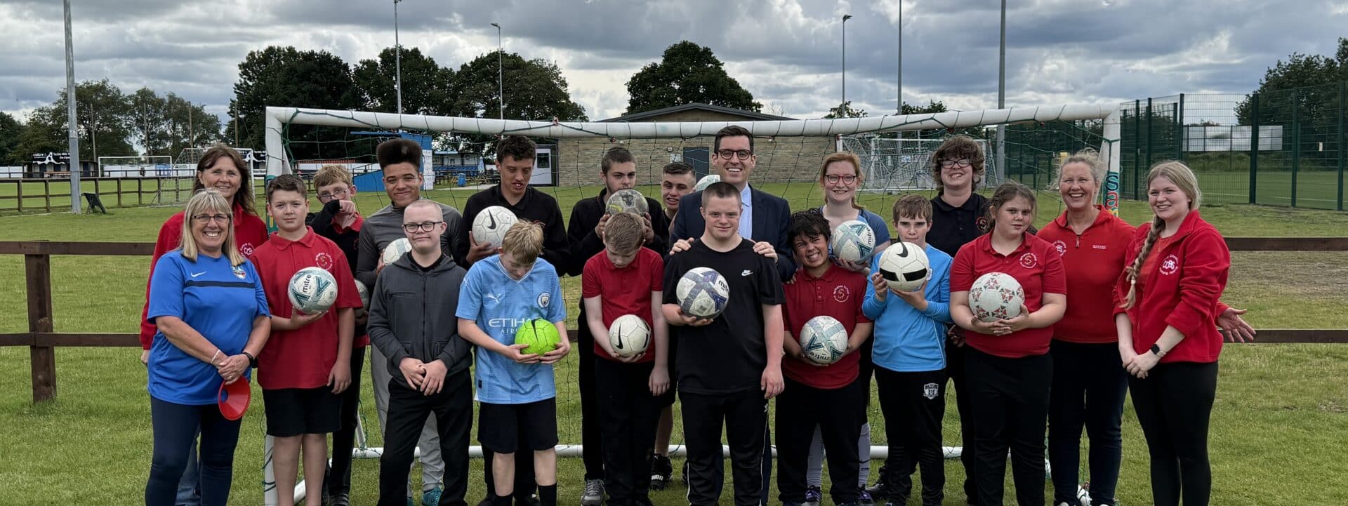 Dan Price stood on a football pitch with young people at Active Buddies - SWAP Fund