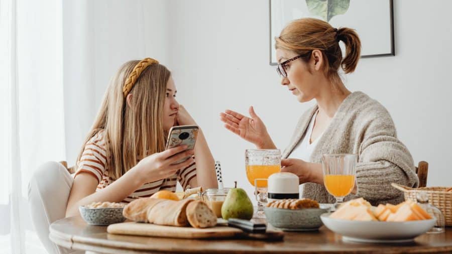 Parent or guardian talking to teenage daughter who is on her phone