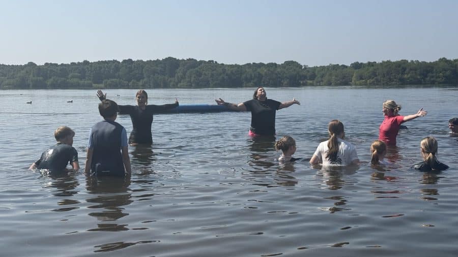 A group of young people in open water being taught safe swimming.